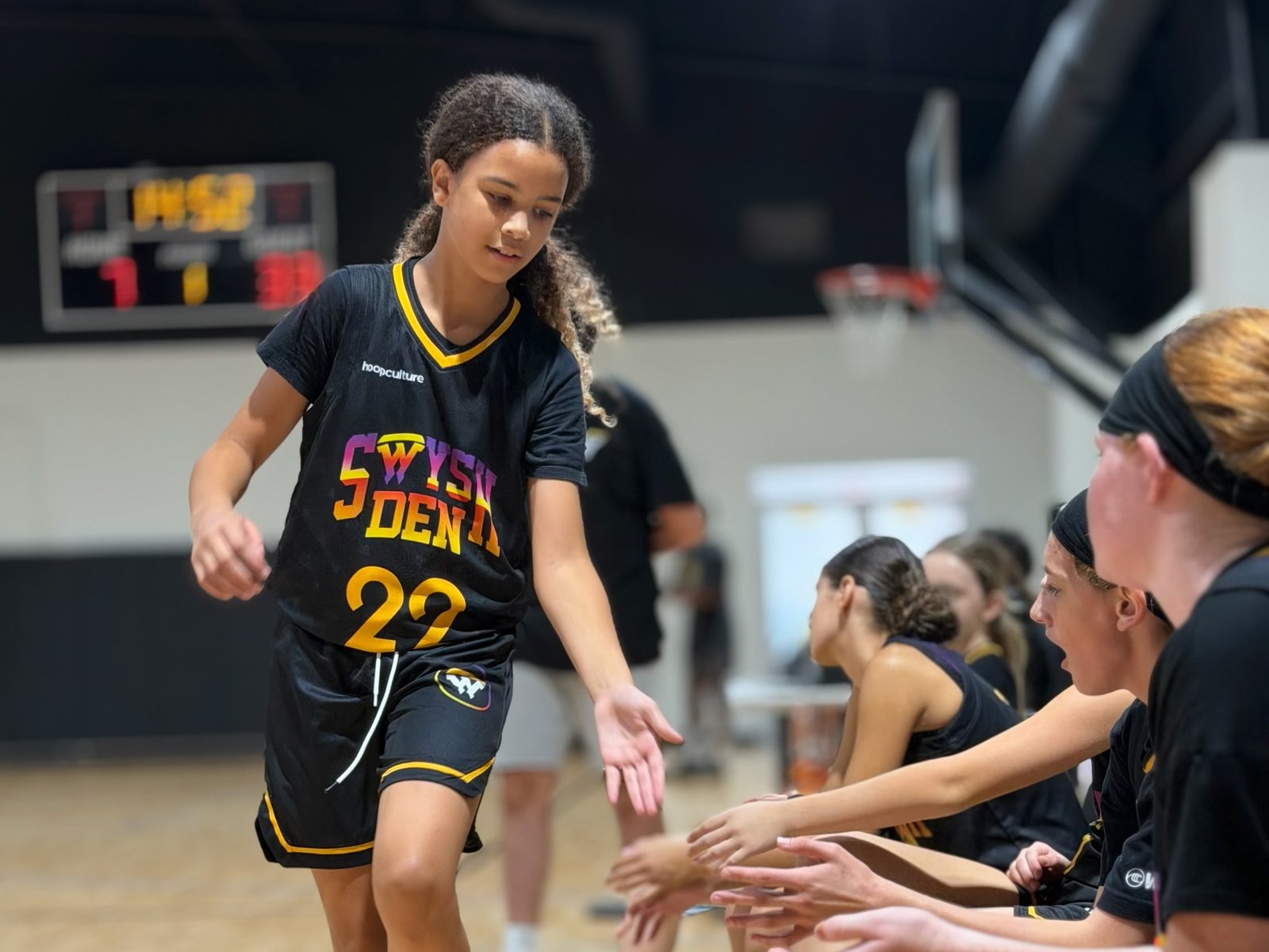 A Swysh Den Club Team player high-fiving teammates on the bench