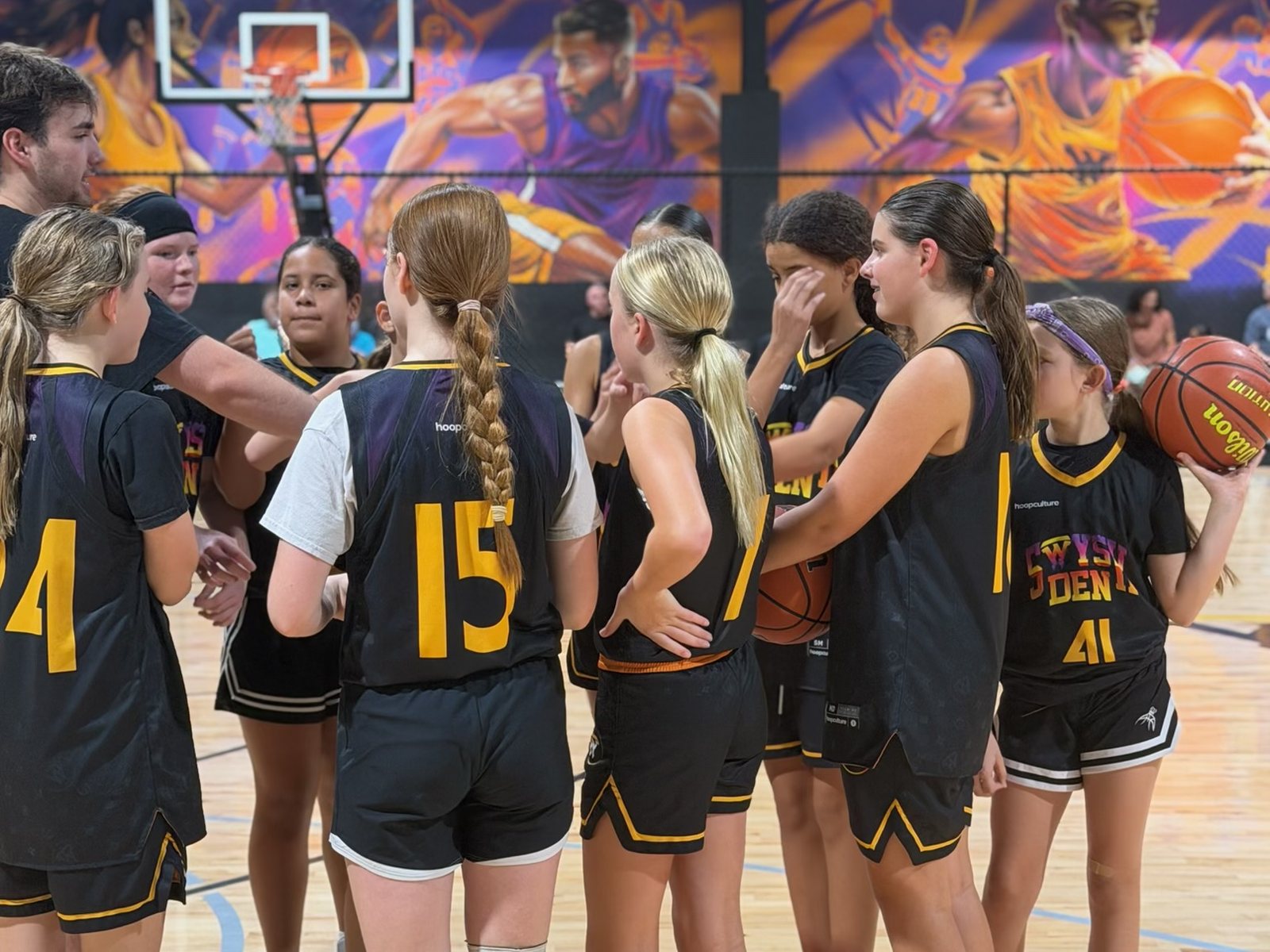 Swysh Den Club Team players gathered in a huddle on the court