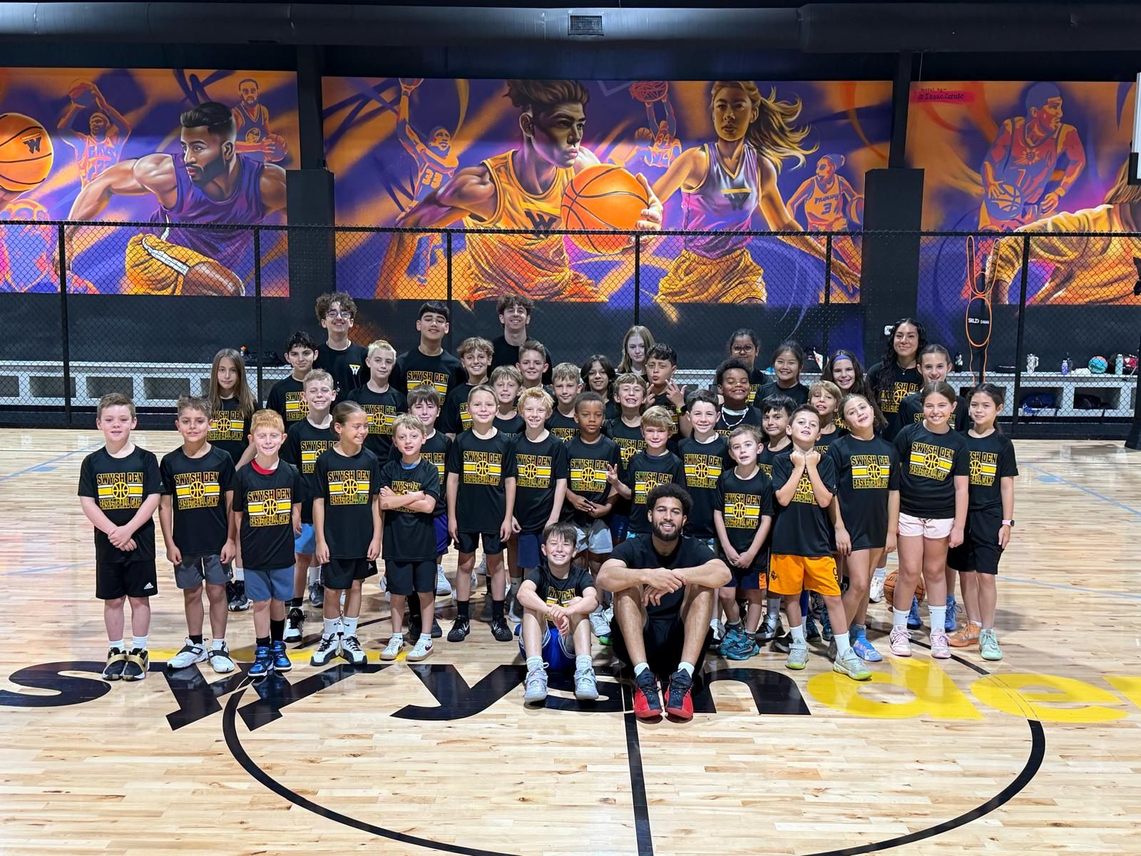 Full team of Swysh Den summer camp kids posing together on the court with a coach